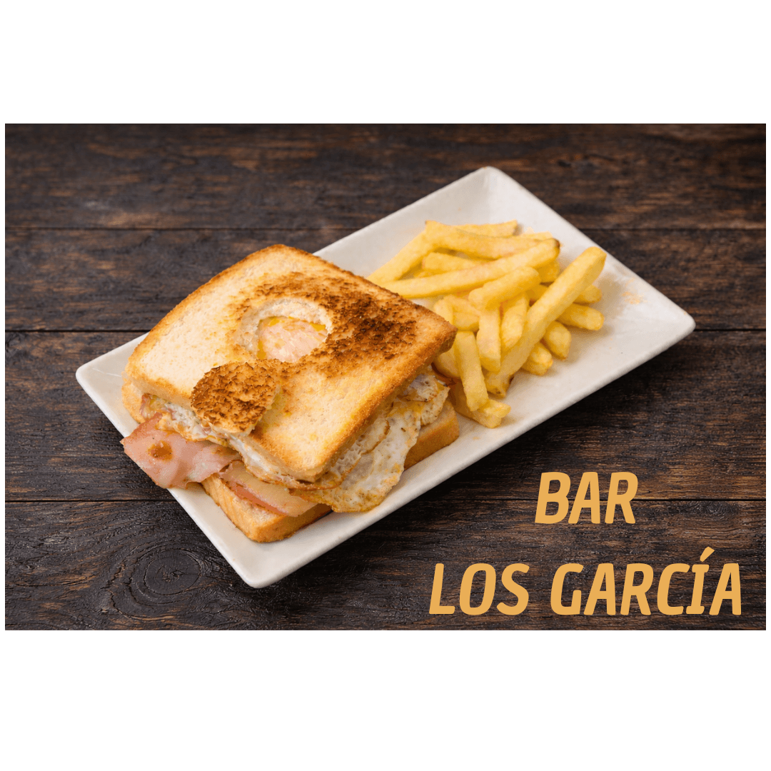 Sándwich tostado de jamón y huevo con patatas fritas del Bar Los García sobre madera.